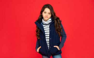 express emotion. winter fashion. funny unpleased kid with curly hair in puffer waistcoat.