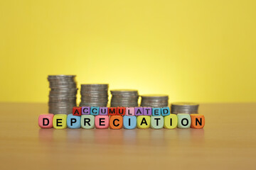 ACCUMULATED DEPRECIATION wordings on colorful cubes with coins stacked at the back 