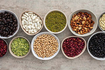 Obraz na płótnie Canvas Different types of legumes in bowls, yellow peas and chickpeas , colored beans and lentils, mung beans, top view, copy space