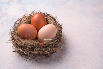 Three chicken eggs in a nest on a light background.