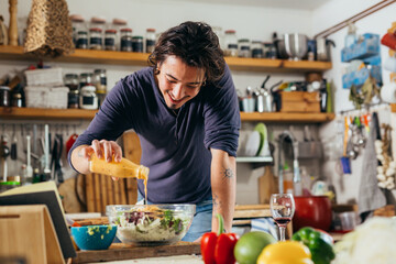 man dressing salad in his kitchen
