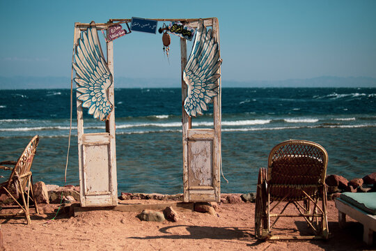 Creative decoration in the seaside cafe in Dahab: old wooden doors and wings in front of the sea,  Dahab, Egypt