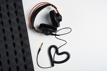 Loving Music, blogging concept background. Headphones with heart shaped cable on white background with copy space and acoustic foam panel, flat lay