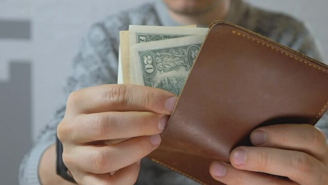 Male get US dollar bills from pocket-sized and foldable wallet made of leather. Banknote. Business or financial concept. Money or cash revenue. Investment and success, financial
