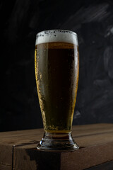 Cup full of Beer. Freezing Beer on a wooden desk and grey background