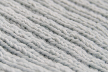 Close-up of hand-knitted garment (2x2 rib stitch) in pale blue. Diagonal view.