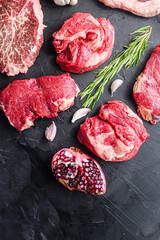 Alternative raw beef steak cuts with top blade, chuck roll and rump steak, with herbs and pomegranate top view .