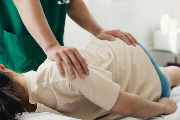 A doctor or physiotherapist helps to heal a young woman's back. and give advice within the...
