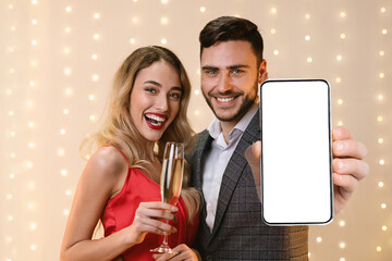 Beautiful millennial couple celebrating anniversary, showing cellphone, mockup