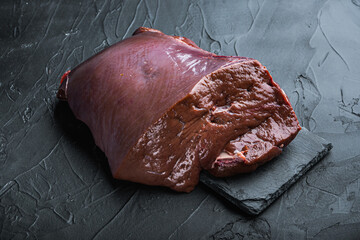 Raw beef liver on black background
