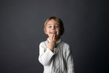 Cute little toddler boy, showing THANK YOU gesture in sign language on gray background, isolated image, child showing hand sings
