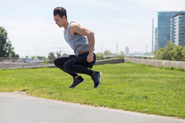Fototapeta na wymiar Fit athletic man jumping up on a public park