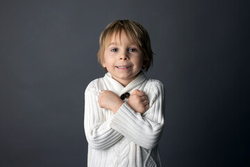 Cute little toddler boy, showing  I LOVE YOU gesture in sign language on gray background, isolated...