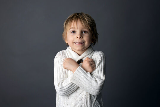 Cute little toddler boy, showing  I LOVE YOU gesture in sign language on gray background, isolated image, child showing hand sings