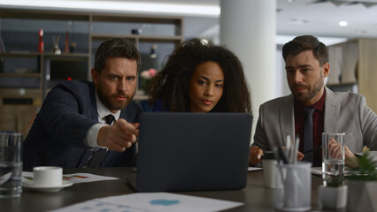 Obraz premium Diverse finance team brainstorm in office. Colleagues using laptop analyze data.