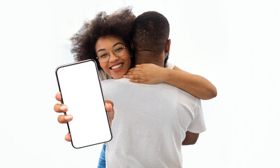 Pretty black lady hugging her boyfriend and showing smartphone, mockup