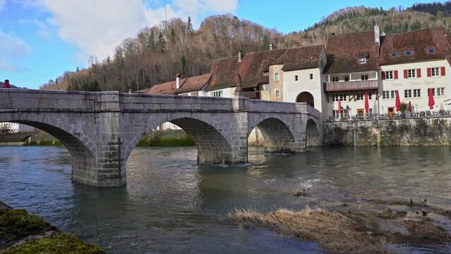 Medieval village Saint-Ursanne, Canton Jura, with beautiful facades of historic houses and stone bridge over river Doubs. Movie shot February 7th, 2022, Saint-Ursanne, Switzerland.
