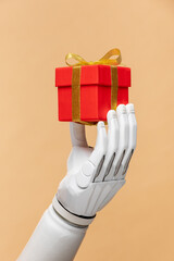 a bionic prosthetic arm or forearm in white on a beige background holds a red gift, prosthetics of...