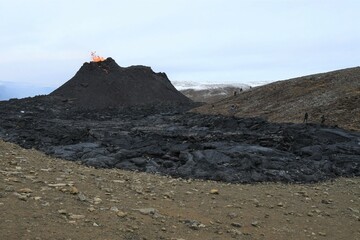 Erupting crater at Fagradalsfjall eruption in Iceland, with a lava flow in front.