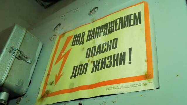 Old russian high voltage electrical warning sign inside the abandoned Soviet underground bomb shelter, old Soviet Cold war bunker, apocalypse, medium handheld close up shot