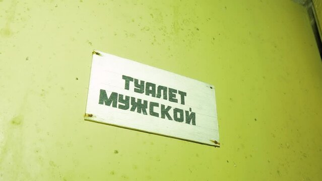 Mans toilet sign (in russian) inside the abandoned Soviet underground bomb shelter, old Soviet Cold war bunker, apocalypse, medium handheld shot