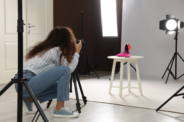 Professional photographer taking picture of stylish shoes in studio