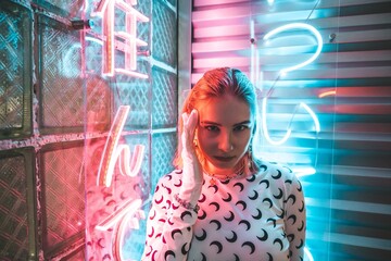 Silhouette of a young woman posing in a room with a neon lamp. Slender modern model in a beautiful pose on a purple-blue background with airbrushes