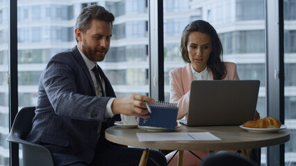 Successful corporate team brainstorming using laptop notepad by window office.