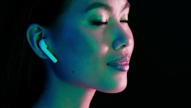 Young Asian Woman Listening Music In Wireless Airpods Earphones In Neon Light
