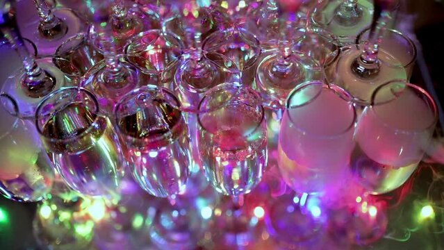 Pyramid of champagne glasses. The tower is undercut by bright lights. Full glasses of sparkling wine at a restaurant party. Holiday, wedding, birthday, event. Dry ice. Champagne with smoke
