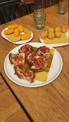 Neapolitan food dishes.
Some toast with tomato, basil and garlic, in the foreground.
Behind it are some croquettes stuffed with potato.