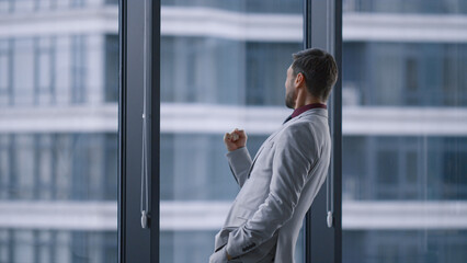 Overjoyed man celebrating business success victory in window office building.