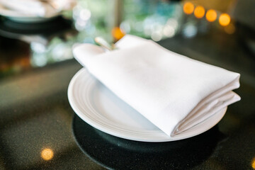 English afternoon tea table with white napkin, cutlery and plate on the black granite tabletop.