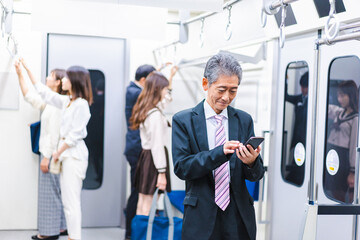 電車内でメールを送るビジネスマン