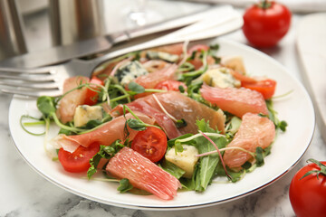 Delicious pomelo salad with prosciutto served on white marble table, closeup