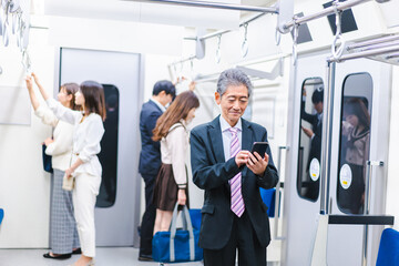 電車内でメールを送るビジネスマン