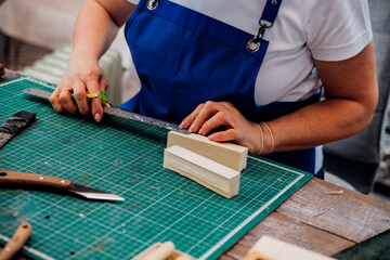 A female carpenter marks details with a pencil and cuts wood with a knife in a carpentry or homemade workshop.Workplace.