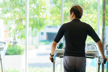 Active Asian sportsman making a cardio exercise by running on the treadmill.