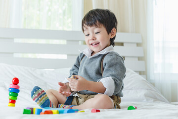 Happy asian little boy on bed.