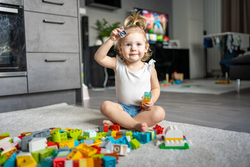 Caucasian child a little girl is playing in the constructor at home. Educational toys for children.