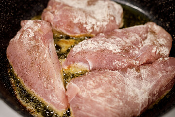 Raw turkey fillet frying in a pan.
