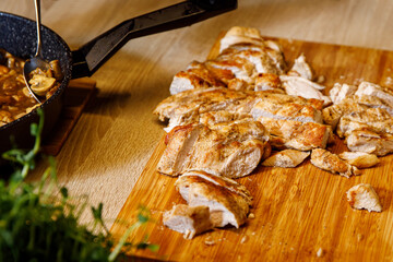 Sliced chicken pieces on a wooden tray.
