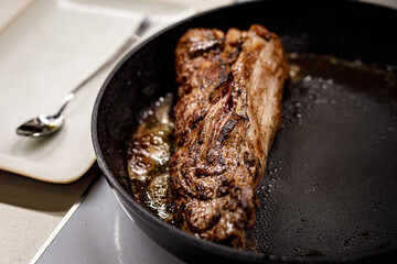 A piece of beef is fried in a pan.