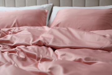 Fototapeta na wymiar Bed with beautiful pink silk linens, closeup