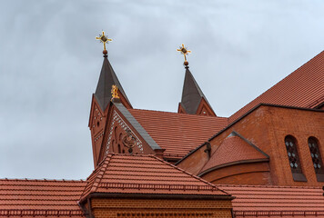 Roof of red brick catholic Church of St. Simon and St. Helena with big cloudy sky in Minsk, Belarus