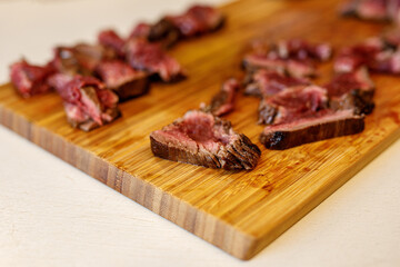 sliced beef pieces on a wooden tray.