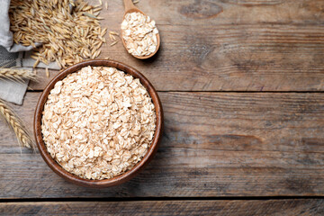 Bowl with oatmeal on wooden table, flat lay. Space for text