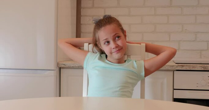 the girl sits in the kitchen and smiles. child is happy at home