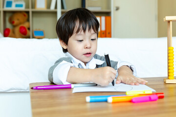 Happy asian little boy sitting alone doing homework, Elementary school and homeschooling concept