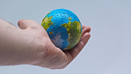 partial view of man holding small globe in hand isolated on grey
